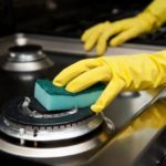 cleaning the stove with a sponge