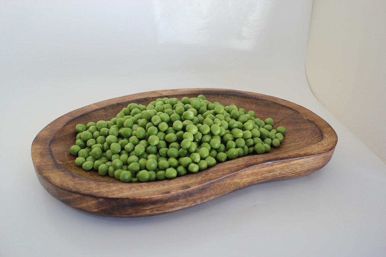 Petits pois dans une assiette en bois