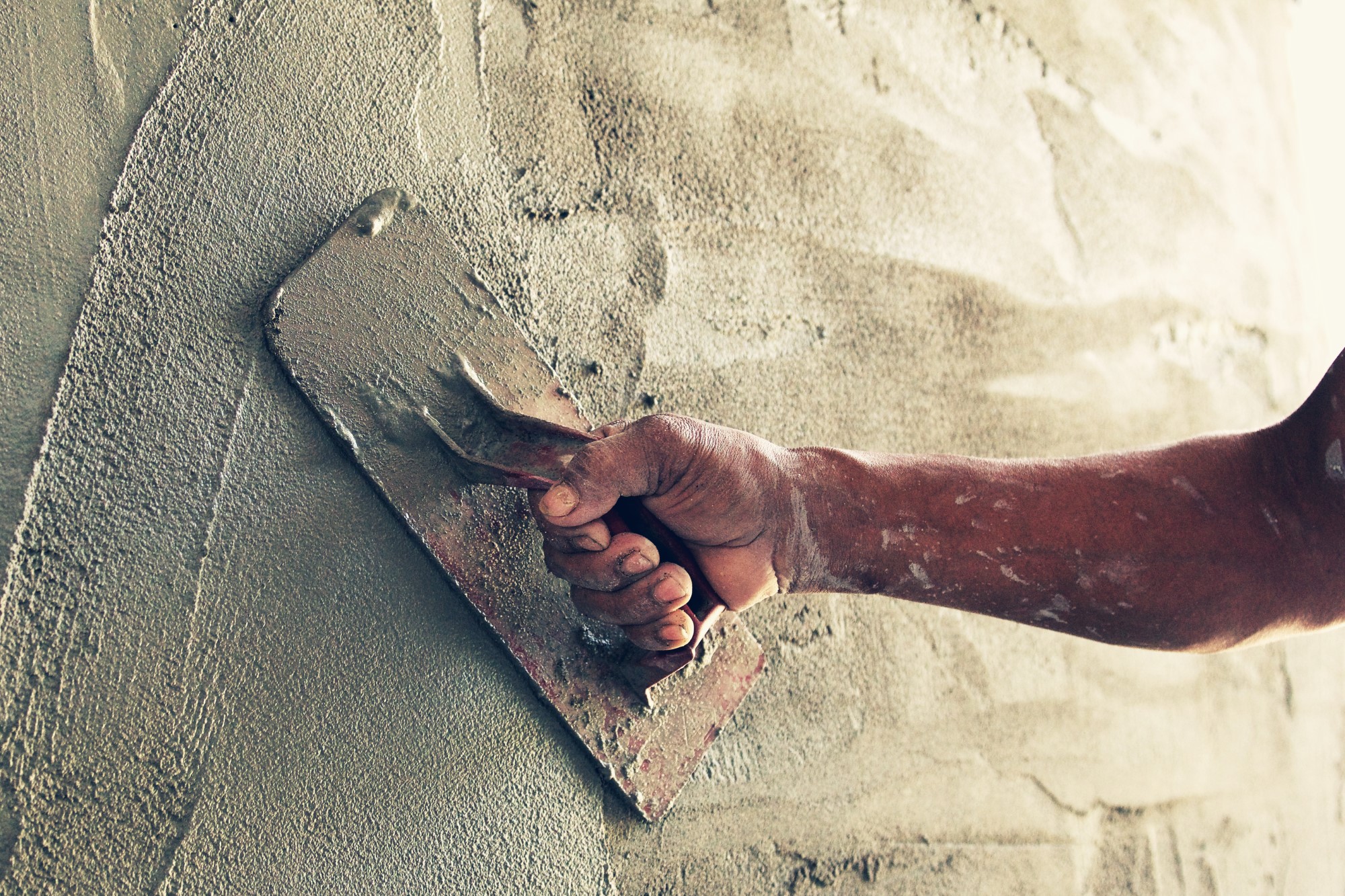 Trabajador de la construcción enyesando cemento en la pared